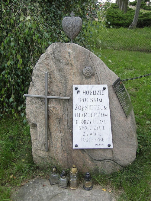 Obok kościoła , przy wejściu na cmentarz znajduje się głaz narzutowy z tablicą z 1989 roku ; poświęcona jest poległym żołnierzom i harcerzom .